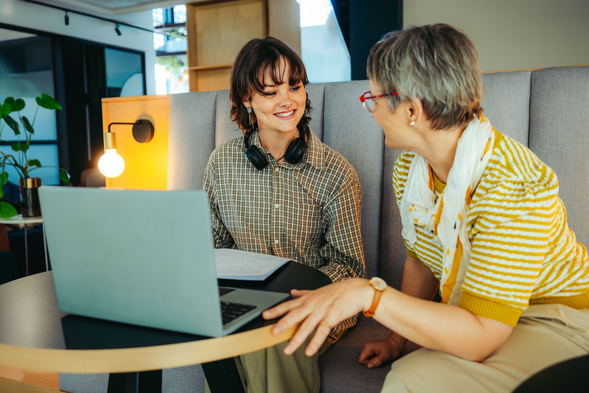 Female teacher helping a student with a project in a modern classroom setting, fostering collaboration and learning through technology and personal interaction